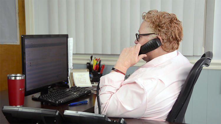 customer service representative answering phone and inputting request on computer screen in office