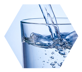 close up of water pouring into a glass on blue background