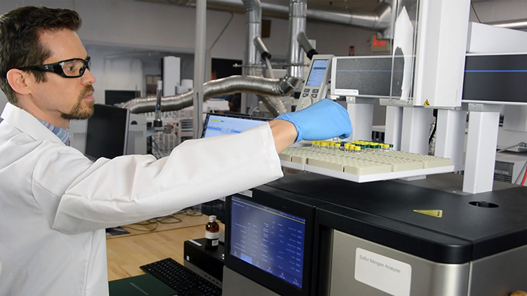 quality control chemist testing chemical standard vials with autosampler machine in chemical lab