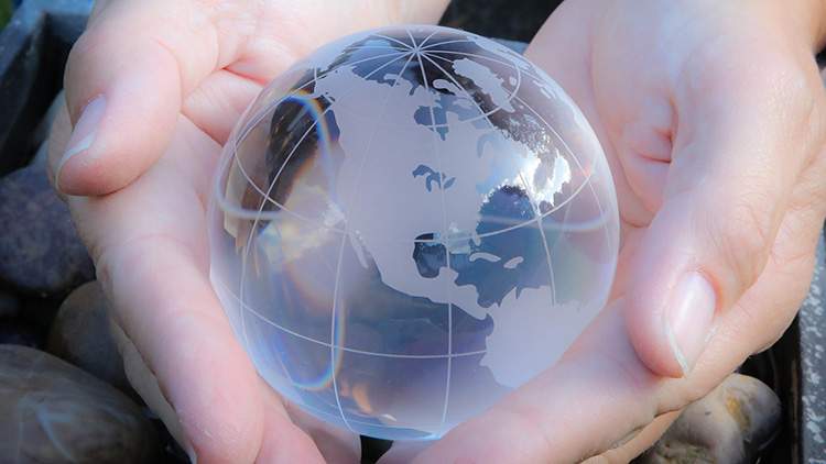 small clear glass globe figure resting in two hands
