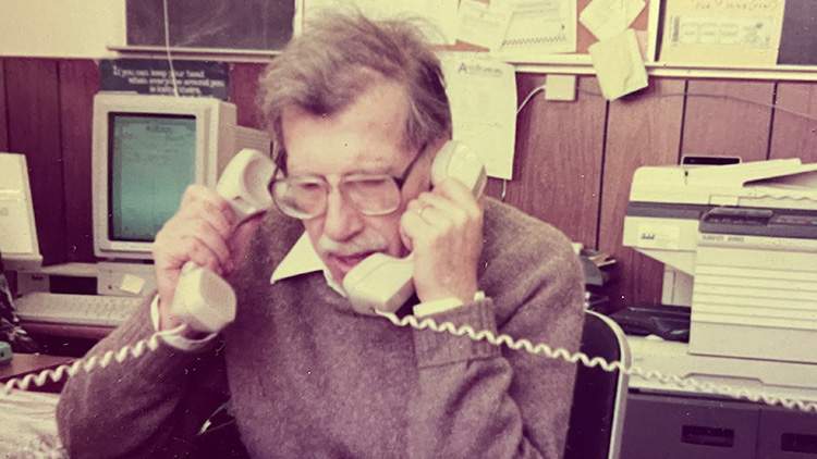 vintage photo of AccuStandard founder Michael Bolgar in an office answering two phones at once