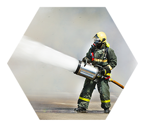 Firefighter extinguishing a large fire, standing in front of a wall of fire and wear protective clothing