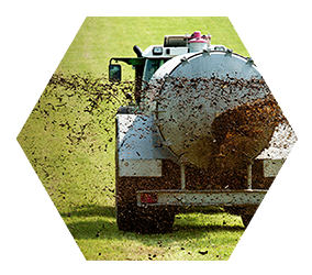 biosolids being spread from a truck onto soil on a farm